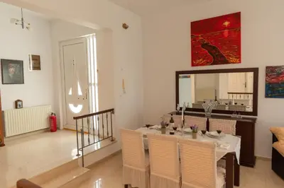 a dining room with a table with chairs and a mirror at Villa George Rhodes in Archangelos