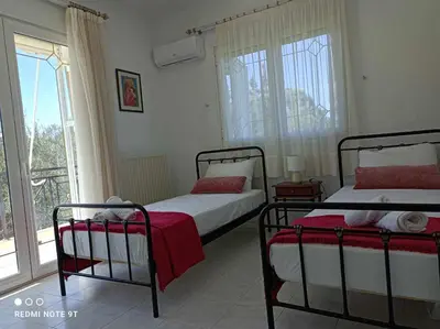 a bedroom with two beds and a window at Villa George Rhodes in Archangelos