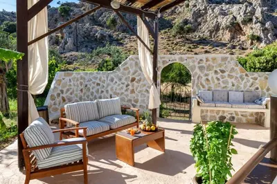 a patio with two couches and a stone wall at Atlantic Cave Haven-Seaside, Fully Equipped in Kolimbia