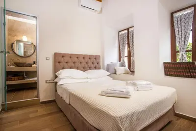 a bedroom with a bed with white sheets and a mirror at The Knight's House Old Town Rhodes in Rhodes Town