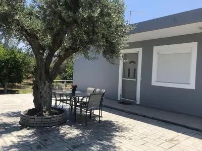 a table and chairs under a tree next to a building at Secret Edem in Kolimbia