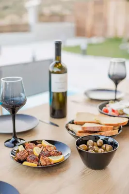 a table with plates of food and a bottle of wine at Villa Tranquility in Psinthos