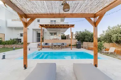 a pergola over a swimming pool in a backyard at Villa Tranquility in Psinthos