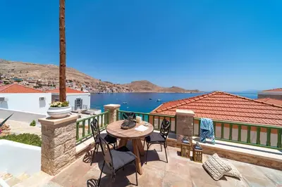 a patio with a table and chairs and the ocean at Muse Clio in Halki