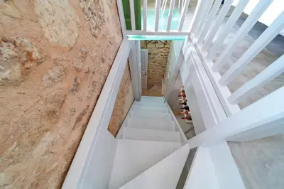 a staircase in a house with white stairs and a stone wall at Muse Clio in Halki