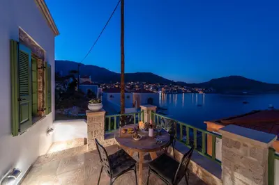 a table on a balcony with a view of the water at Muse Clio in Halki