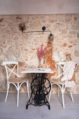 a table and chairs in a room with a stone wall at Muse Clio in Halki