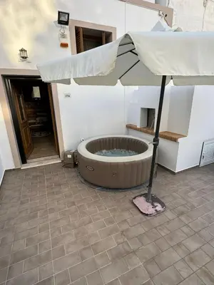 a patio with a hot tub with an umbrella at Traditional House Leventis in Archangelos