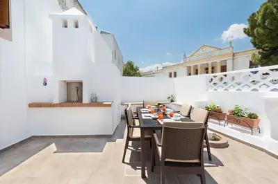 a patio with a table and chairs on a white wall at Traditional House Leventis in Archangelos