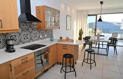 a kitchen with wooden cabinets and a table with chairs at Villa Vitabel sea view in Lindos in Líndos