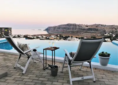 two chairs and a table next to a pool at Villa Vitabel sea view in Lindos in Líndos