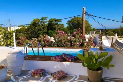 a bench with pillows sitting next to a swimming pool at The Summer Pink House in Lachania