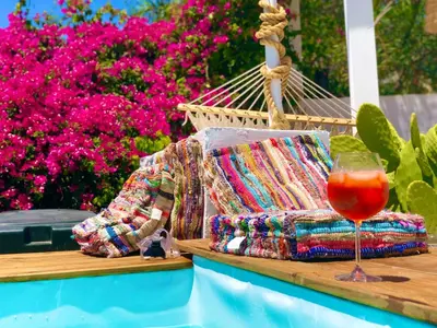 a drink sitting on a wooden tray next to a hammock at The Summer Pink House in Lachania