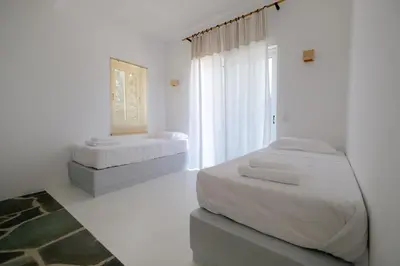 a white bedroom with two beds and a window at Elia Suites in Triánta