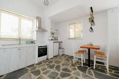 a kitchen with white cabinets and a table and chairs at Elia Suites in Triánta