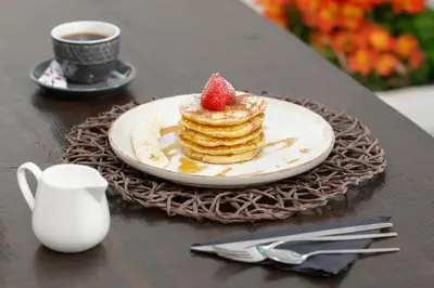 a plate of pancakes with a strawberry on a table at Ancient Knights Luxury Suites in Rhodes Town