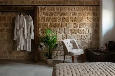 a bedroom with a bed and a chair and a brick wall at Ancient Knights Luxury Suites in Rhodes Town