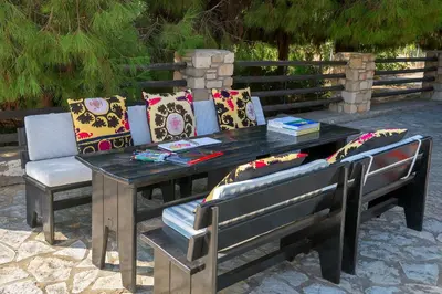a wooden table and bench with pillows on it at Villa Mary's Holiday House in Pefki Rhodes