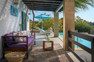 a patio with a couch and an umbrella and a pool at Villa Mary's Holiday House in Pefki Rhodes