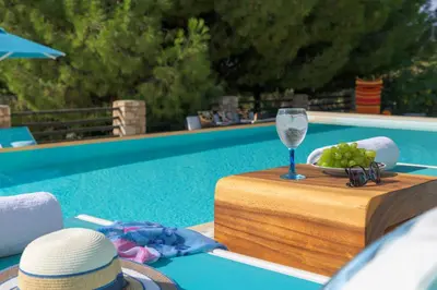 a table with a glass of wine next to a pool at Villa Mary's Holiday House in Pefki Rhodes