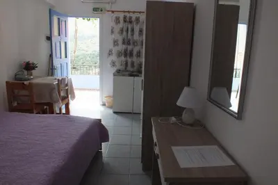 a bedroom with a bed and a table and a door at Anastasia Apartments (Chorio) in Symi