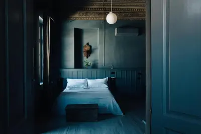 a blue bedroom with a bed with white pillows at 1900 Hotel in Symi