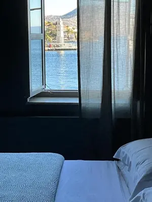 a bedroom with a window with a view of the water at 1900 Hotel in Symi
