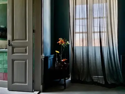 a door with a window and a vase with flowers on a table at 1900 Hotel in Symi