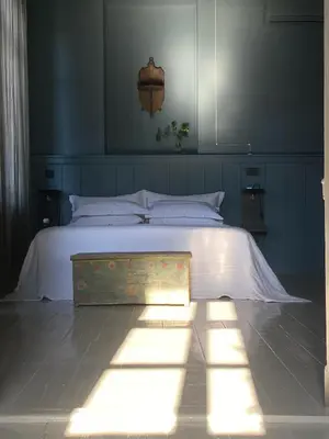 a bedroom with a white bed with a chest on it at 1900 Hotel in Symi