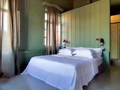 a bedroom with a large bed with white sheets at 1900 Hotel in Symi