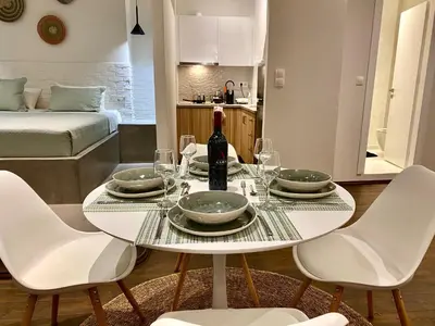 a white table with a bottle of wine and chairs at Rhodes Old Town Harmony Suite in Rhodes Town