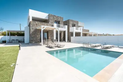 a villa with a swimming pool in front of a house at Kiotari Fresh in Kiotari