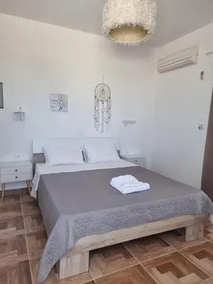a white bedroom with a bed and a clock on the wall at 12 senses faliraki sea view in Faliraki
