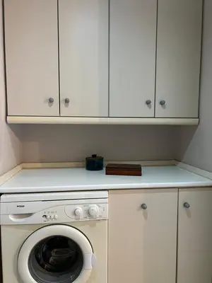 a washing machine in a kitchen with white cabinets at Appartment by the beach in Rhodes Town