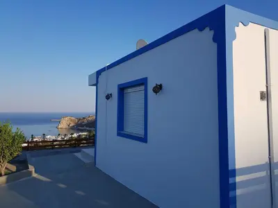 a blue building with a window and a view of the ocean at KIRA'S RESIDENCE PANORAMIC VIEW in Archangelos