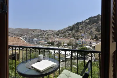 a table on a balcony with a view of a city at Centrale Apartment Symi in Symi