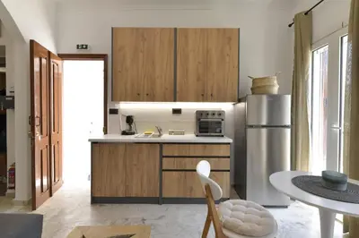 a kitchen with wooden cabinets and a stainless steel refrigerator at Centrale Apartment Symi in Symi