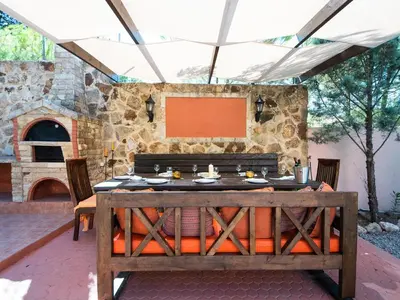 an outdoor dining area with a table and a stone oven at Butterfly Garden Villa in Pastida