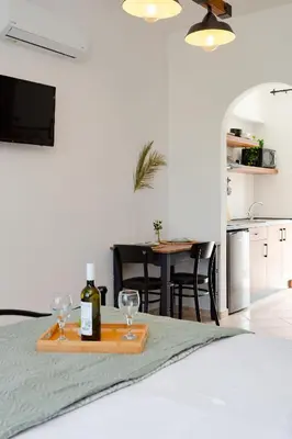 a bedroom with a table with two wine glasses on a bed at Althea Apartments in Kolimbia