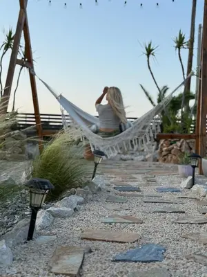 a woman sitting in a hammock on the beach at Althea Apartments in Kolimbia