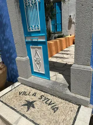 a blue door with a sign on a sidewalk at Villa Sylvia in Symi