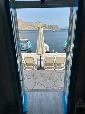 an open door to a patio with an umbrella and water at Villa Sylvia in Symi