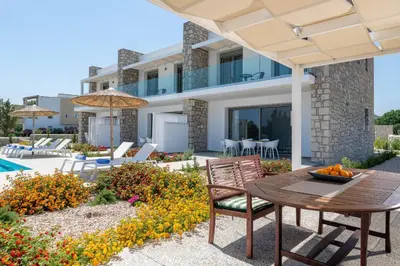a patio with a table and chairs and a house at Gennadi Harmony Suites - 200 m from the sea in Gennadi