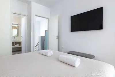 a white bedroom with a bed with two towels on it at Gennadi Harmony Suites - 200 m from the sea in Gennadi