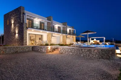 a large house with a stone wall and an umbrella at Gennadi Harmony Suites - 200 m from the sea in Gennadi
