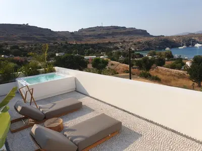 a balcony with two chairs and a swimming pool at AF Lindia Nature Design Hotel in Líndos