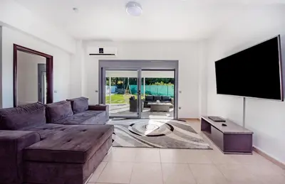 a living room with a couch and a flat screen tv at Dias Luxury Villa in Koskinou