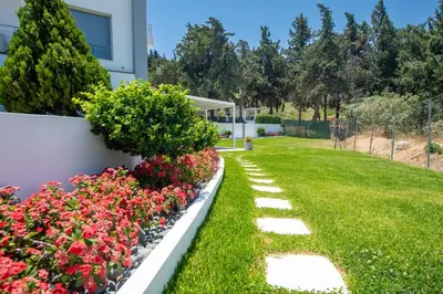 a garden with flowers next to a house at Dias Luxury Villa in Koskinou