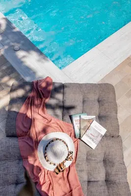 a person sitting on a couch next to a swimming pool at Dias Luxury Villa in Koskinou
