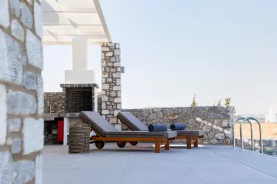 a patio with two lounge chairs and a fireplace at Grand Blue Villas Lachania in Lachania